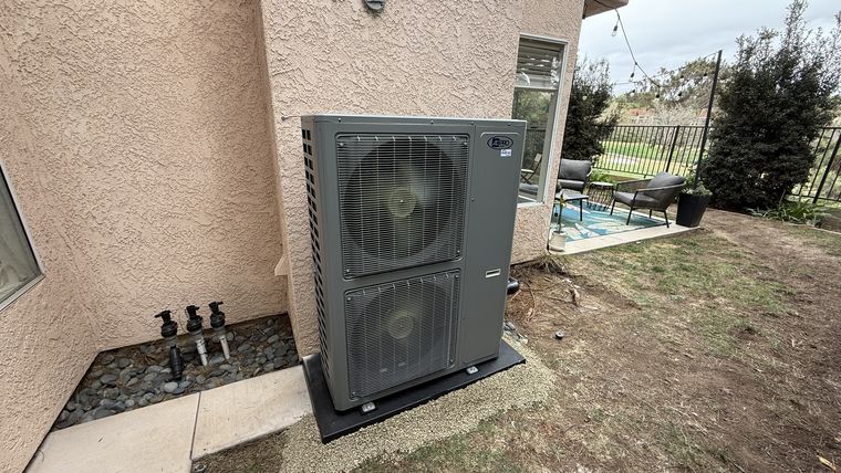 Dual-fan heat pump condenser in yard