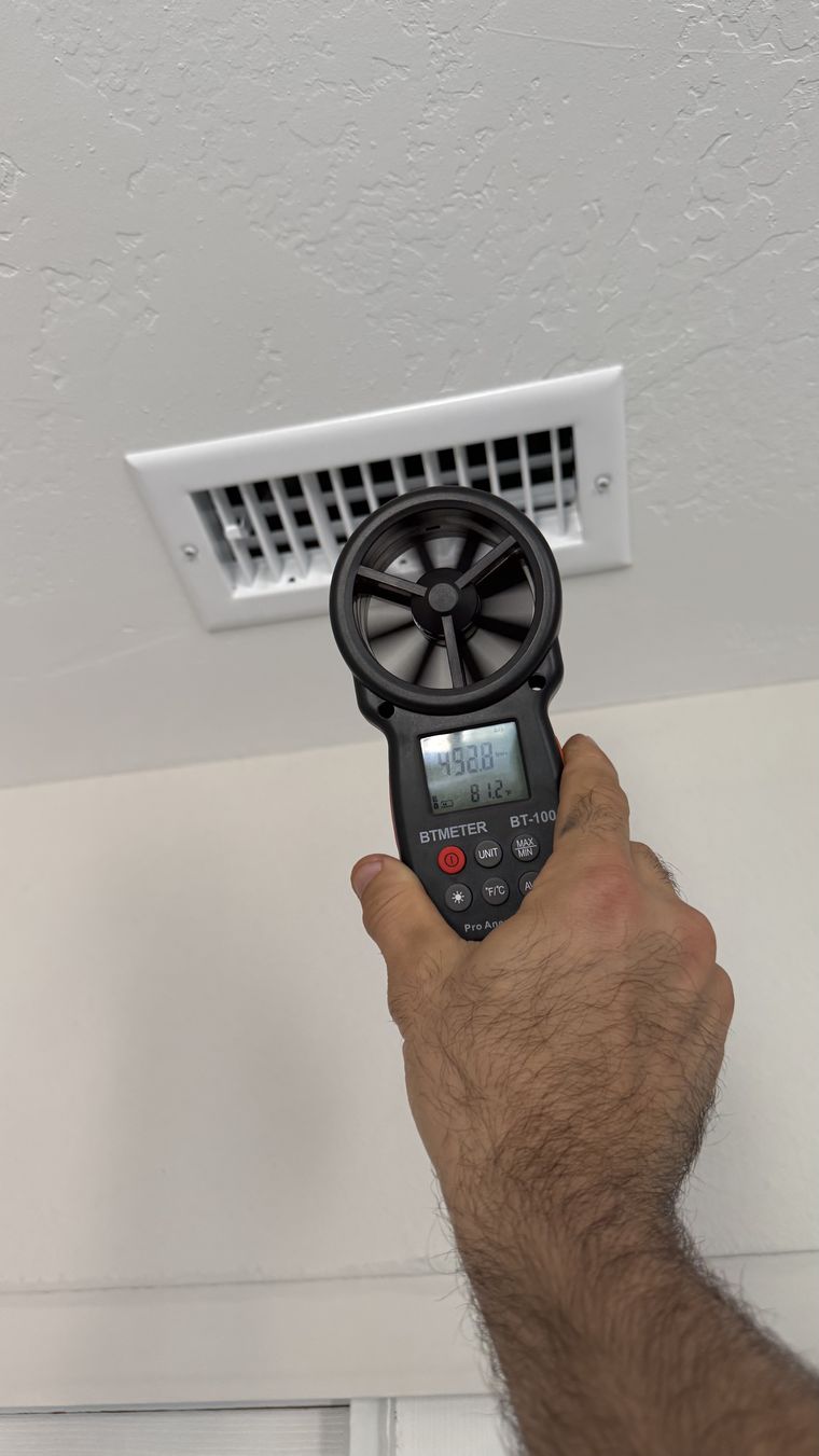 Tech measuring airflow at ceiling register