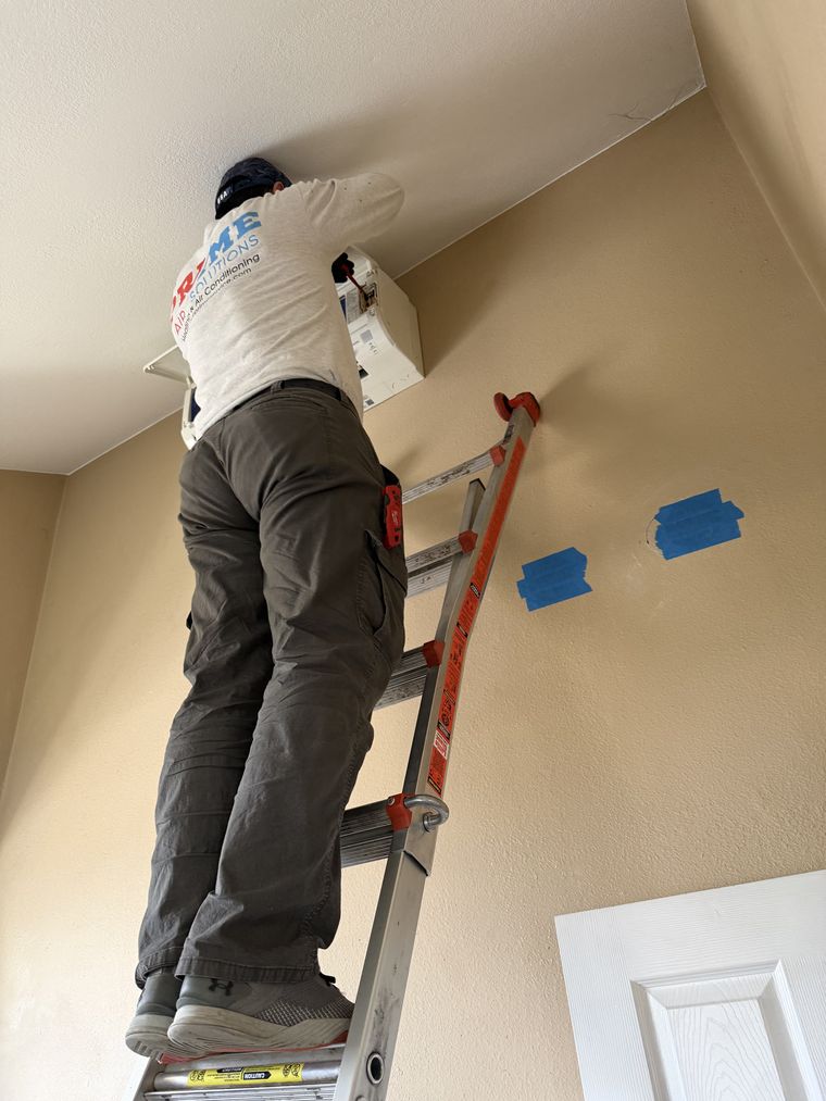 Tech on ladder installing indoor mini-split head